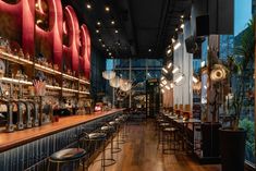 a bar with lots of stools and lights hanging from the ceiling