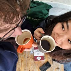 two people sitting at a table with cups of coffee