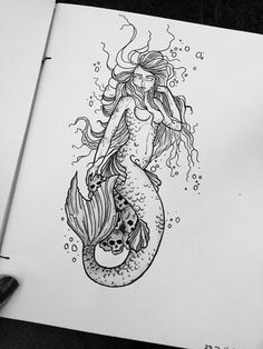 a drawing of a mermaid sitting on top of a white piece of paper next to a pen