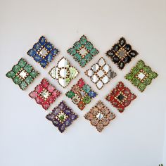 a group of nine square shaped brooches on a white surface, each with different colored stones