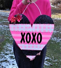 a woman holding a heart shaped box with the word xoxo written on it