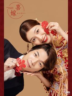 two people posing for a photo with red paper hearts on their foreheads in front of a beige background