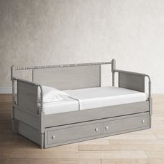 a daybed with two drawers underneath it on the floor next to a white wall