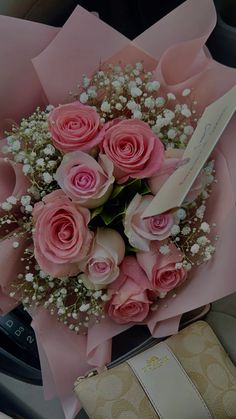 a bouquet of pink roses and baby's breath sits on the dashboard of a car