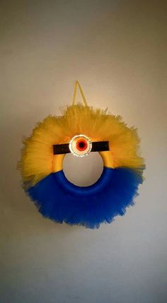 a yellow and blue toy hanging from the ceiling with an evil eye on it's head