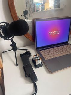 an open laptop computer sitting on top of a desk next to a microphone and batteries