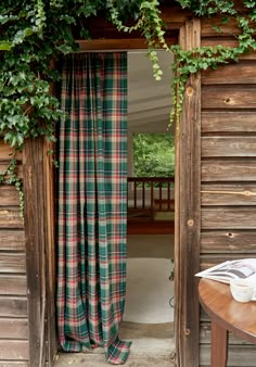 an open door to a room with green plants growing on the wall and curtains hanging over it