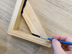 a person is using a brush to paint the edges of a wooden frame with black tape