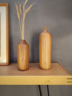 two wooden vases sitting on top of a table next to a framed photo and mirror