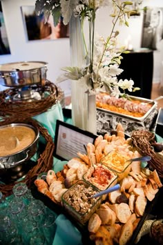 an assortment of food is displayed on a table with flowers and other items in the background