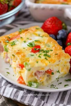 a slice of quiche on a plate with strawberries and blueberries in the background