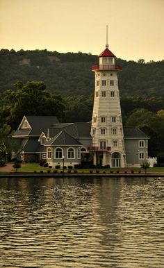 a large white building sitting on top of a lake next to a lush green hillside