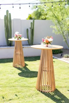 two wooden tables sitting on top of a grass covered field next to a cactus plant