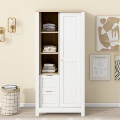 a white armoire in a room with pictures on the wall and towels hanging up