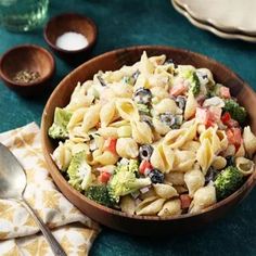 a wooden bowl filled with pasta salad on top of a table