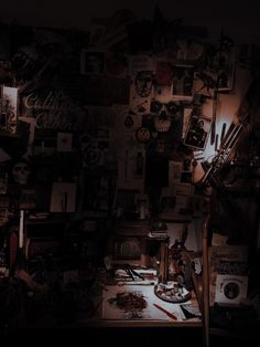 a dark room filled with lots of clutter and pictures on the wall above it