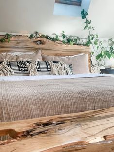 a bed with pillows and blankets on top of it next to a potted plant