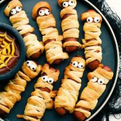 hot dogs wrapped in croissants with googly eyes and spider web on them