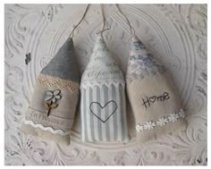 three small cones are hanging on a white lace doily with the word home written on them