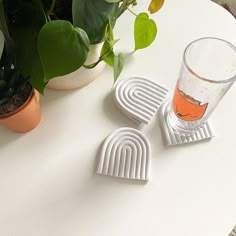 three coasters sitting on top of a white table next to a potted plant