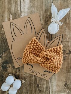 a knitted cat bow tie sitting on top of a cardboard box next to eggs