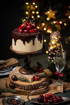 a chocolate cake with cherries on top is sitting on a table next to other desserts