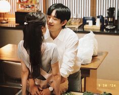 a man and woman standing next to each other in front of a table with food on it