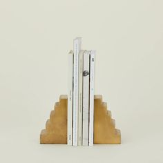 three books are stacked on top of each other in front of a white wall and beige bookcase