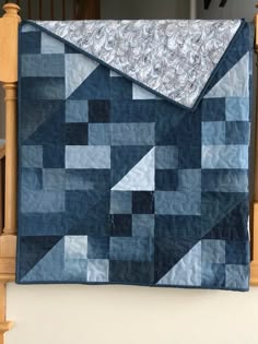 a blue quilted blanket sitting on top of a wooden banister