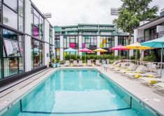 an empty swimming pool with chairs and umbrellas in front of the building's windows