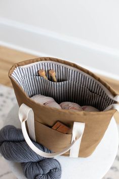 a tote bag is sitting on top of a ball of yarn and some knitting needles