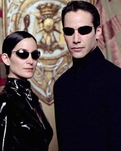 the man and woman are wearing black sunglasses, one is standing next to each other