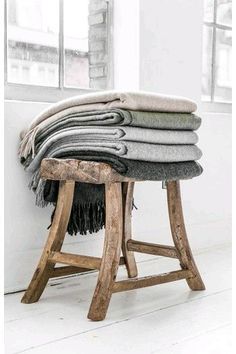 several blankets stacked on top of a wooden stool