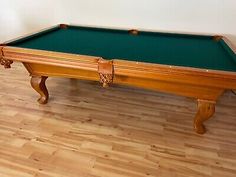 an antique pool table with green cloth and wooden legs