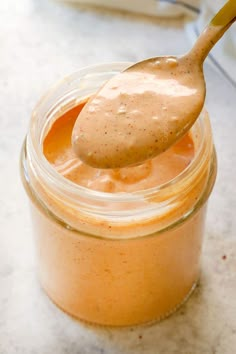 a spoon full of peanut butter sitting on top of a jar