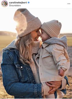 a woman holding a small child in her arms and wearing a hat on top of her head