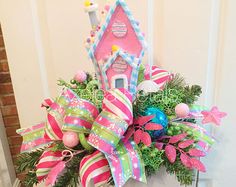 a christmas wreath decorated with pink and green ribbons, candy canes, ornaments and a gingerbread house