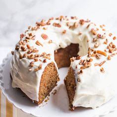 a carrot cake with white frosting and pecans on top, cut in half