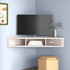 a flat screen tv mounted to the side of a wall next to a footstool