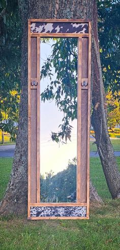 a mirror sitting in the grass next to a tree