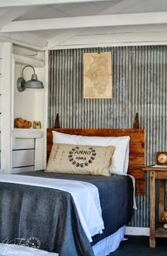 a bed sitting in a bedroom next to a wooden table and wall mounted light fixture