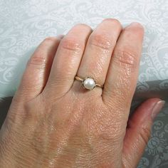 Classic and elegant, this vintage style pearl engagement ring exudes a timeless elegance with a simple band of gold set with a glowing pearl in a crown of hearts. Hand-wrought from recycled 14kt gold, a slim gold band holds a 6.5-7mm cultured creamy white freshwater pearl in a detailed 14kt gold filigree heart-crown setting. Pearl engagement rings are not only unique, but hold a special meaning as pearls symbolize wisdom, purity, harmony and loyalty. This ring would also make a lovely gift for o Solitaire Pearl Ring For Anniversary, Anniversary Solitaire Pearl Ring With Round Cut, Timeless Pearl Ring With Prong Setting For Anniversary, Timeless 14k Gold Round Band Pearl Ring, Classic Round Pearl Ring With Pearl Drop, Classic Pearl Ring With Pearl Drop, Elegant Solitaire Pearl Promise Ring, Timeless White Pearl Ring In 14k Gold, 14k Gold Timeless Pearl Ring With Round Band