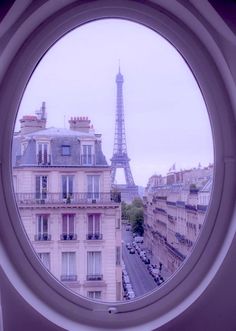 the eiffel tower seen through a round window in an apartment building, paris