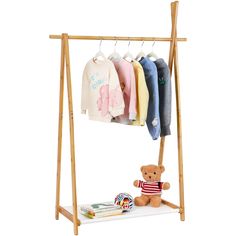 a teddy bear is sitting on a shelf next to some clothes and t - shirts