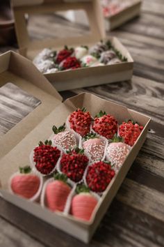 two boxes filled with strawberries on top of a wooden table next to each other