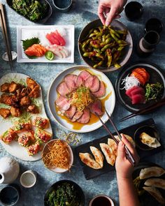 a table topped with plates and bowls filled with different types of food next to chopsticks