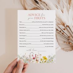 a person holding up a card with advice for firsts written on it next to feathers