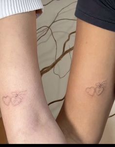 two people with matching tattoos on their legs, one has an apple and the other has a heart