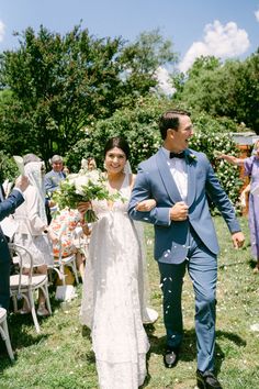 a bride and groom walking down the aisle at their outdoor wedding ceremony with confetti thrown in the air