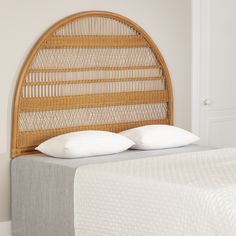 a bed with two pillows on it and a headboard made out of wicker